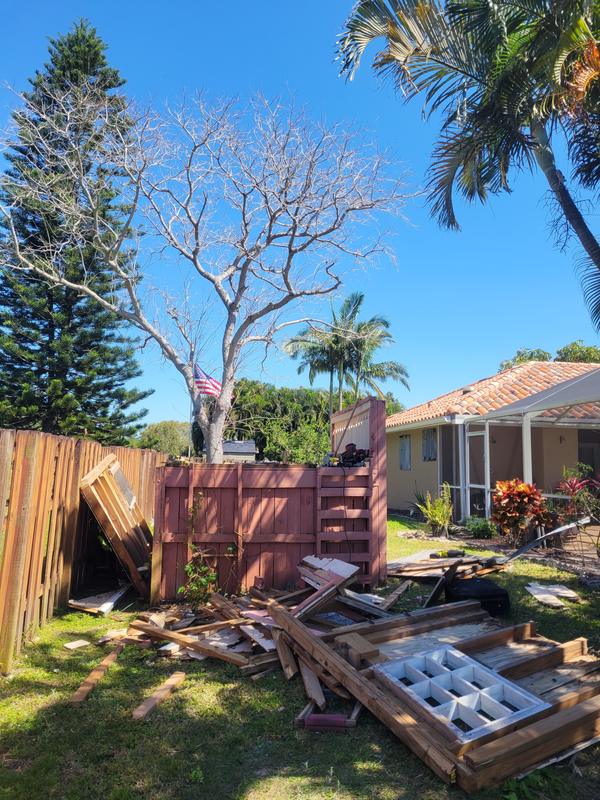 Torn-down wood fence and backyard debris ready for haul-away