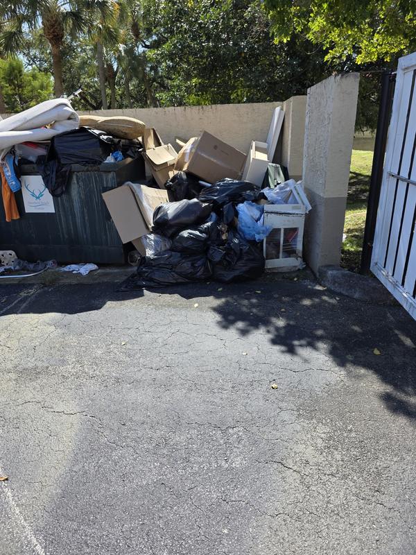 Large pile of household junk and bagged trash in a driveway